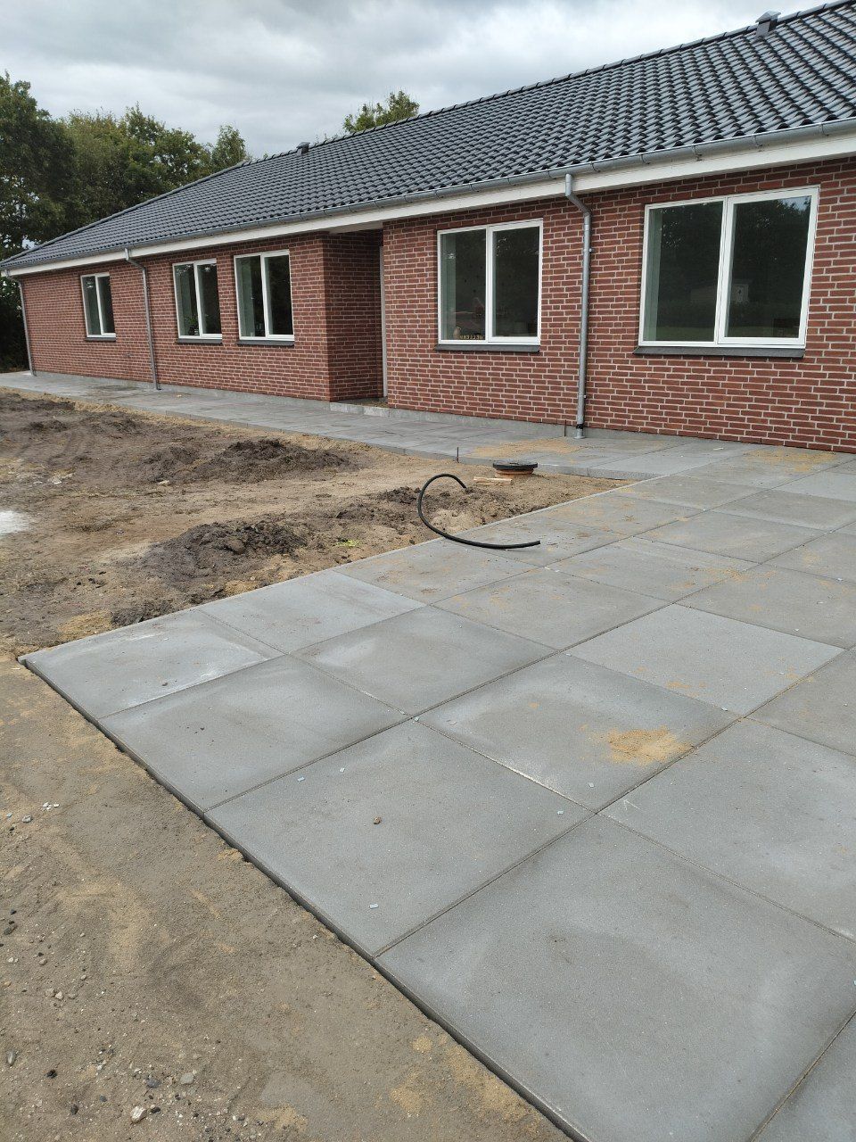 Nylagt belægning med betonfliser langs hus, udført af LS BYG